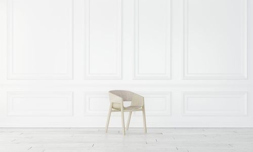 Empty chair against white wall