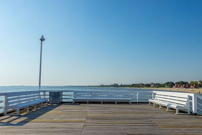 Pier over sea against clear blue sky