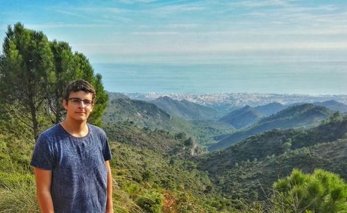 Portrait of young man standing on landscape against sky