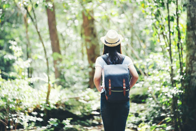 Woman wearing hat standing in forest