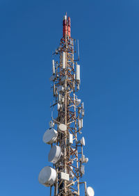 Low angle view of communications tower against clear blue sky