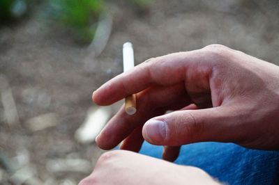 Cropped hand holding burning cigarette