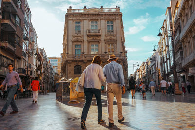 People walking on street amidst buildings in city