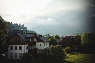 Houses amidst trees and buildings against sky