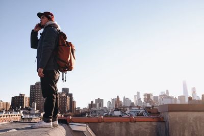 Woman standing on city street against clear sky