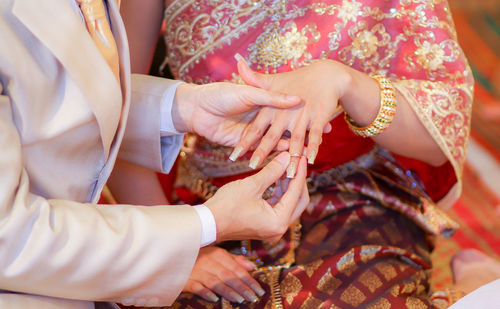 Midsection of wedding couple exchanging finger rings during ceremony