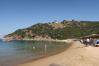 People at beach against clear sky