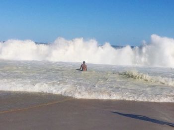 Man surfing in sea against clear sky