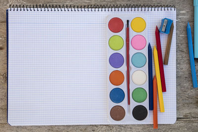 Directly above shot of multi colored pencils and spiral notebook on table