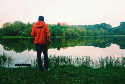 Rear view of man standing by lake against sky