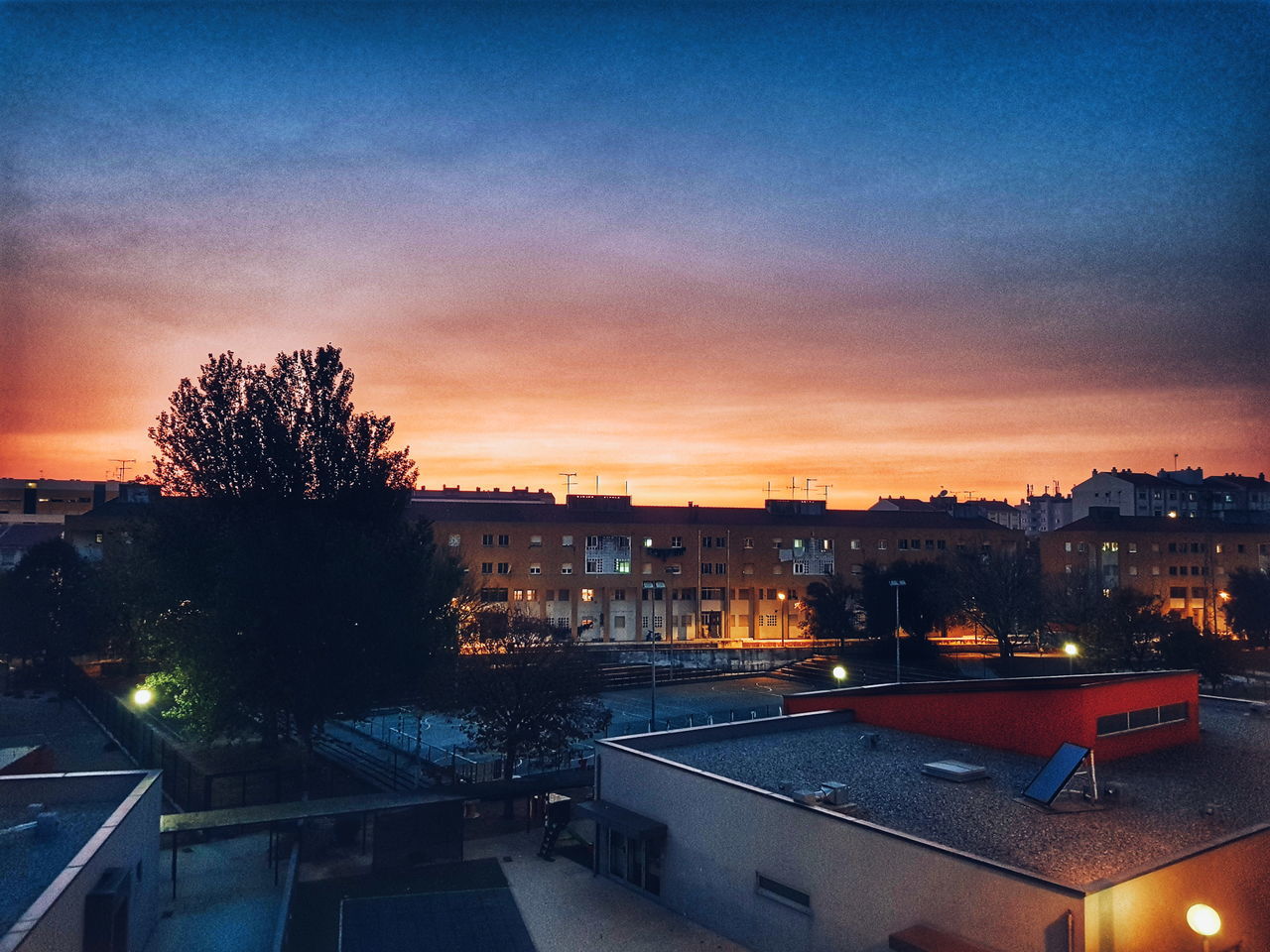 ILLUMINATED CITY AGAINST SKY AT SUNSET