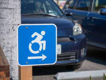 Close-up of road sign against cars on street