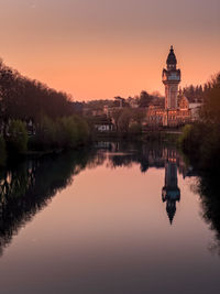 Reflection of buildings in lake during sunset