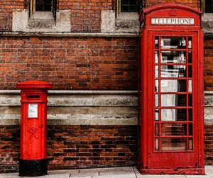 Mailbox and telephone booth against brick wall