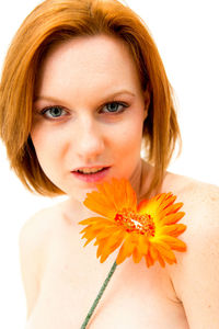 Portrait of shirtless young woman with flower against white background