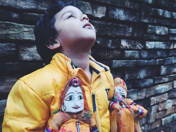 Boy holding puppets and standing against wall