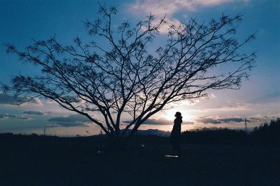 Silhouette man standing on field against sky during sunset