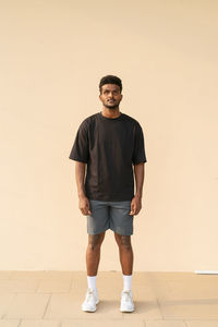 Portrait of handsome young african man wearing oversized black t-shirt full length shot