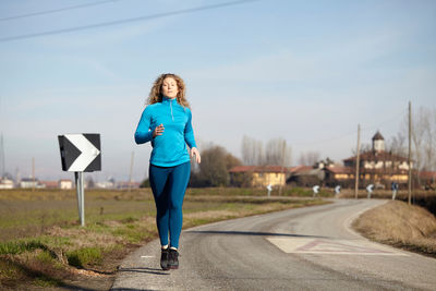 Woman running on road against sky