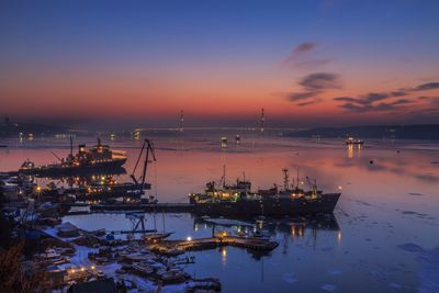 Boats moored at harbor against sky during sunset