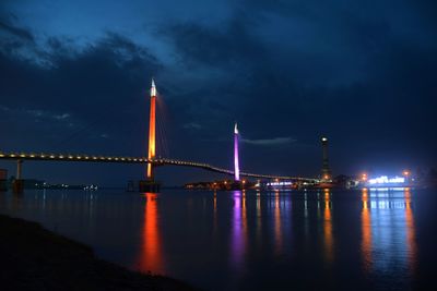 Illuminated bridge over river against sky at night