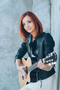 Portrait of young woman playing guitar