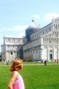 Rear view of woman in front of historical building against sky