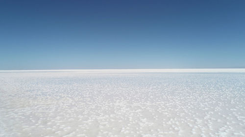 Scenic view of snow against clear blue sky