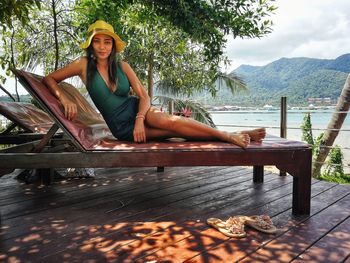 Portrait of woman sitting on wood against mountains