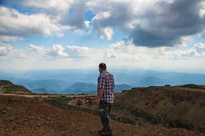 Man dressed for hiking is walking on top of kopaonik mountain, serbia and watching landscape