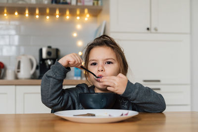 Close-up portrait of cute girl eating food at home