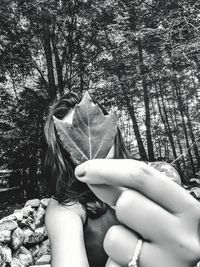 Midsection of woman against tree trunk in forest