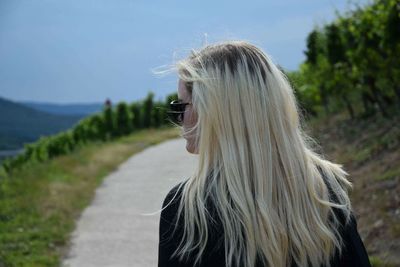 Rear view of young woman standing on country road