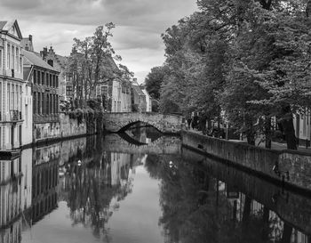 Bridge over river amidst buildings in city against sky