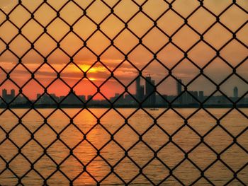 Chainlink fence against sky during sunset