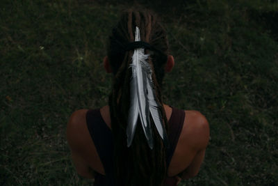 High angle view of feathers in dreadlocks of woman standing on field