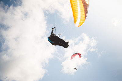 View of man paragliding over landscape against sky