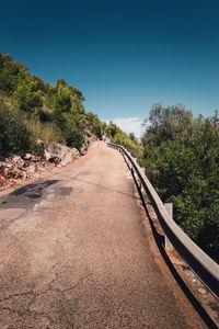 Road amidst trees against clear sky