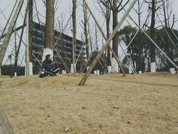 Man sitting in park against sky