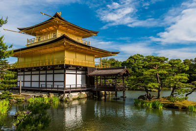 Temple by lake and building against sky