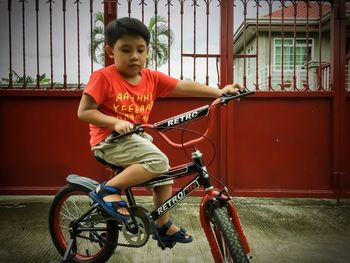 Cute boy riding bicycle on footpath