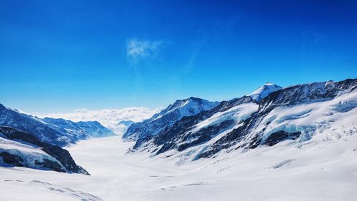 Scenic view of snowcapped mountains against blue sky