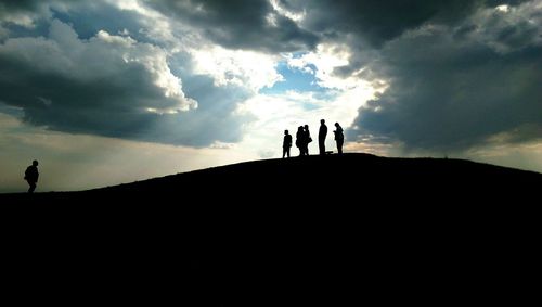 Low angle view of silhouette people against cloudy sky