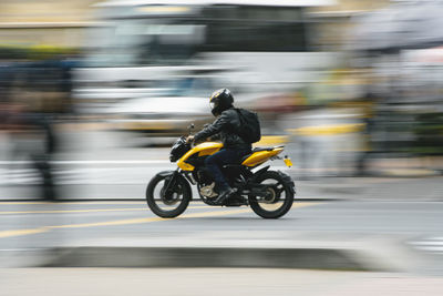 Blurred motion of person riding motorcycle on road