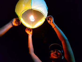 Low angle view of woman holding illuminated lantern at night