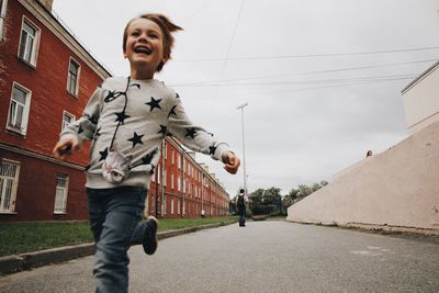 Happy boy running on road in city