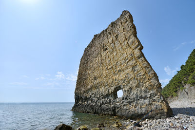 Rock formation in sea against sky