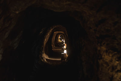 Illuminated tunnel seen through hole in cave