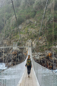 Rear view of man walking on footbridge