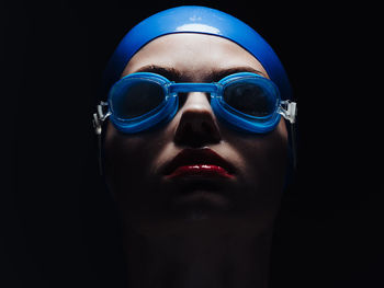Close-up of woman wearing swimming goggles in dark